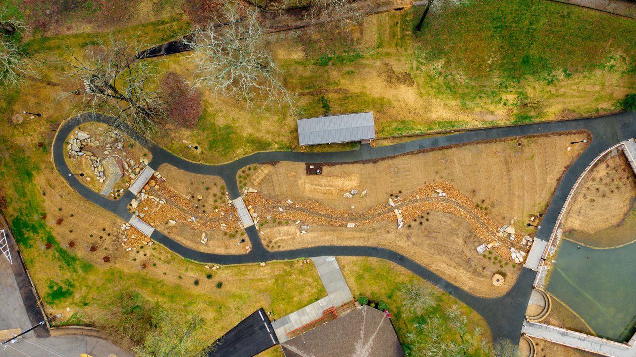 Aerial view of landscaped garden pathways with trees and structures, showcasing detailed greenery.